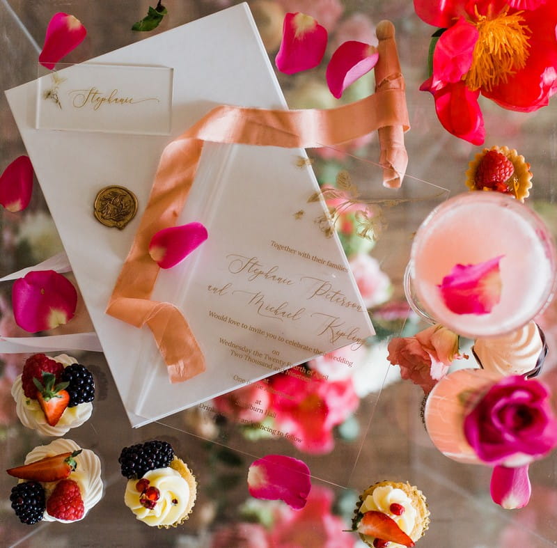 Coral and pink details with small wedding desserts and perspex stationery