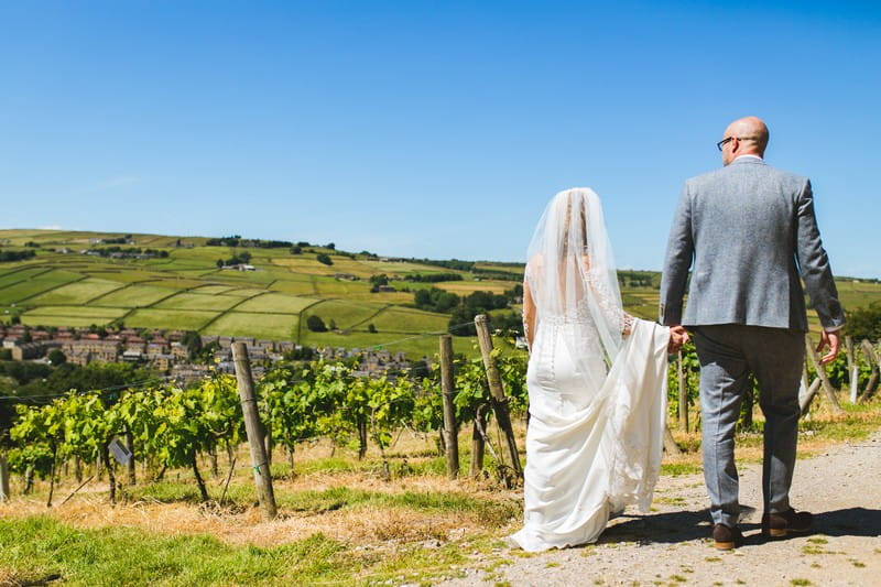Bride and groom holding hands as they walk around Holmfirth Vineyard