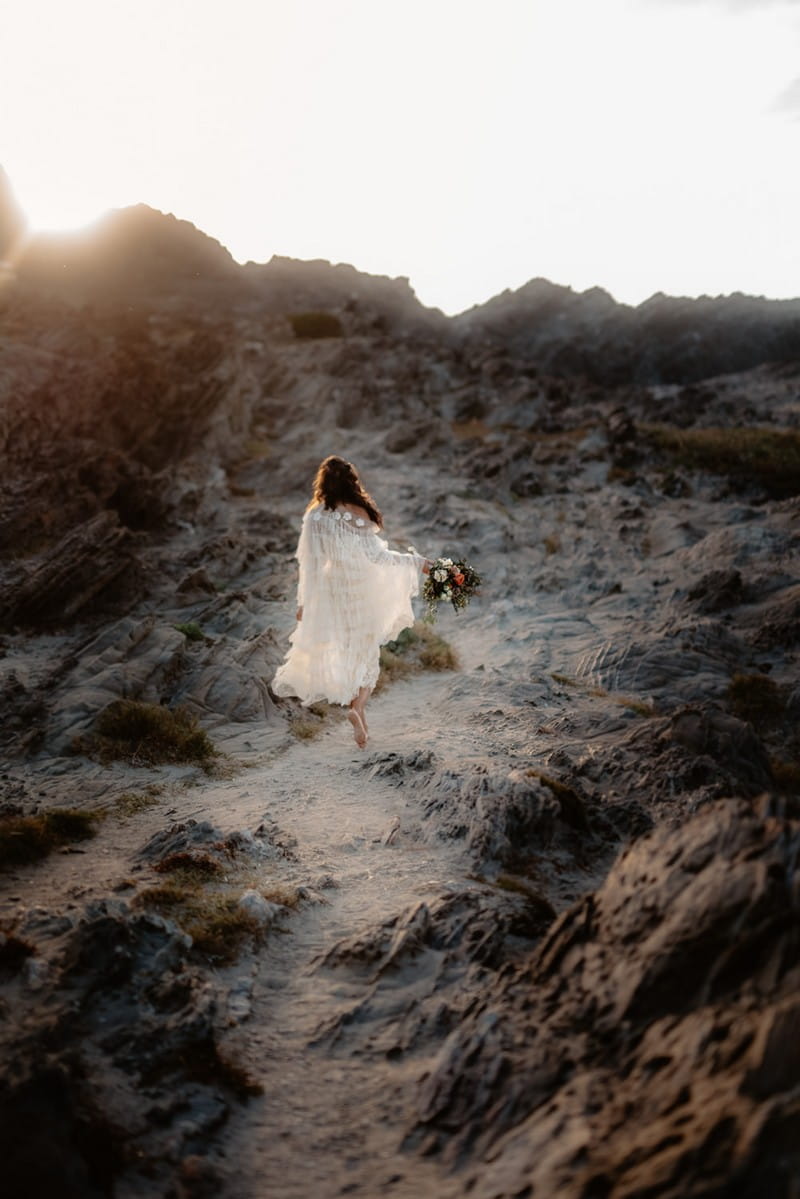 Bride walking up sandy hill on La Pelosa beach