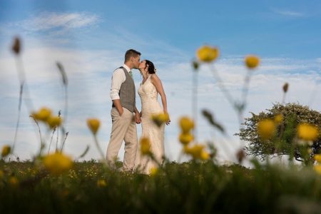 Bride and groom kissing behind yellow flowers - Picture by Linus Moran Photography