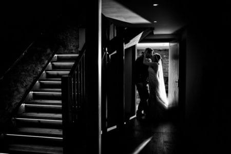 Bride and groom kissing in doorway next to stairs - Picture by Giles Atkinson Photography