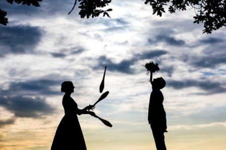 Silhouette of bride juggling clubs and groom balancing bouquet on his chin - Picture by Aaron Storry Photography