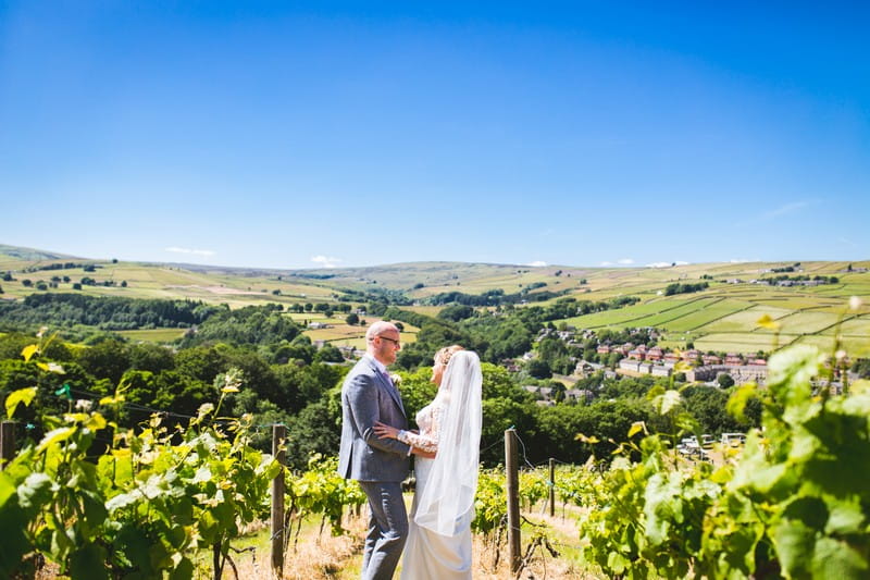 Bride and groom at Holmfirth Vineyard with Holme Valley hills in background