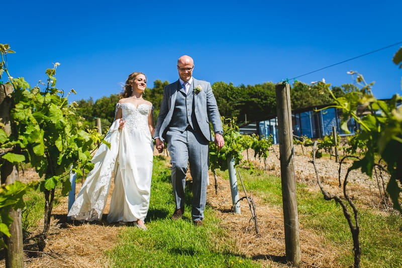 Bride and groom walking through Holmfirth Vineyard
