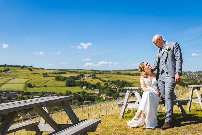 Bride and groom sitting on picnic bench at Holmfirth Vineyard
