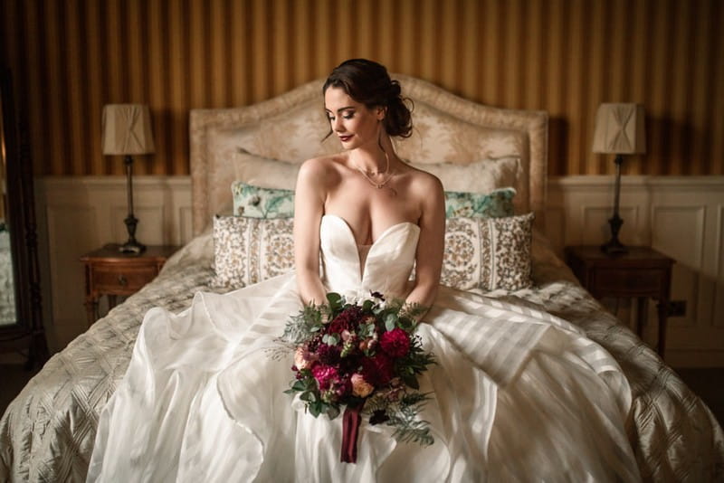 Bride sitting on bed holding bouquet