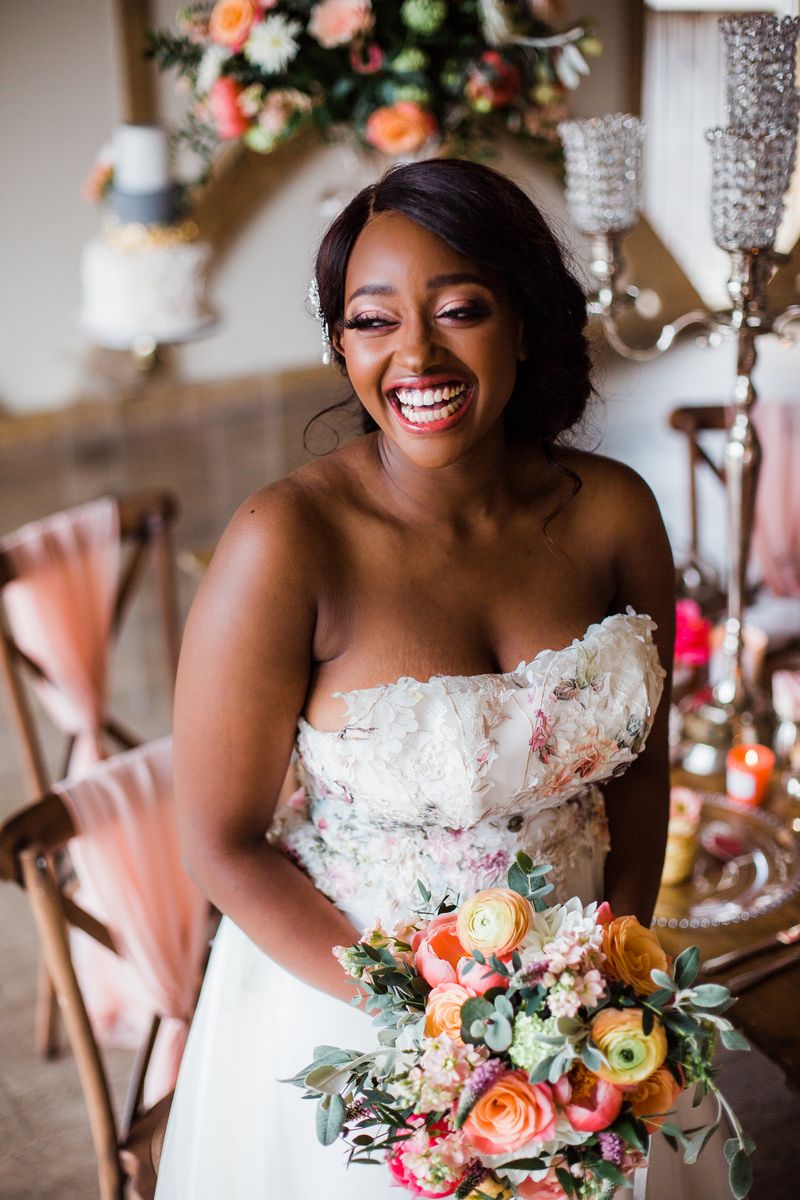 Bride with big smile sitting holding bouquet