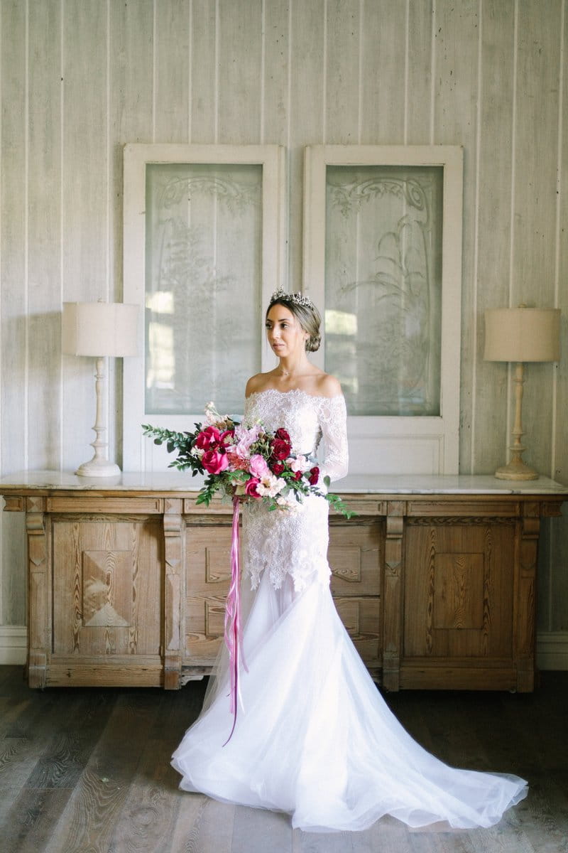 Bride standing holding burgundy and pink wedding bouquet
