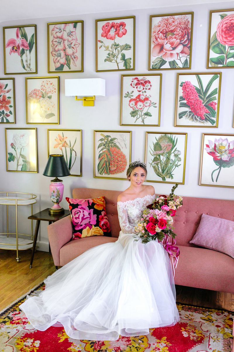 Bride sitting on pink couch holding bouquet