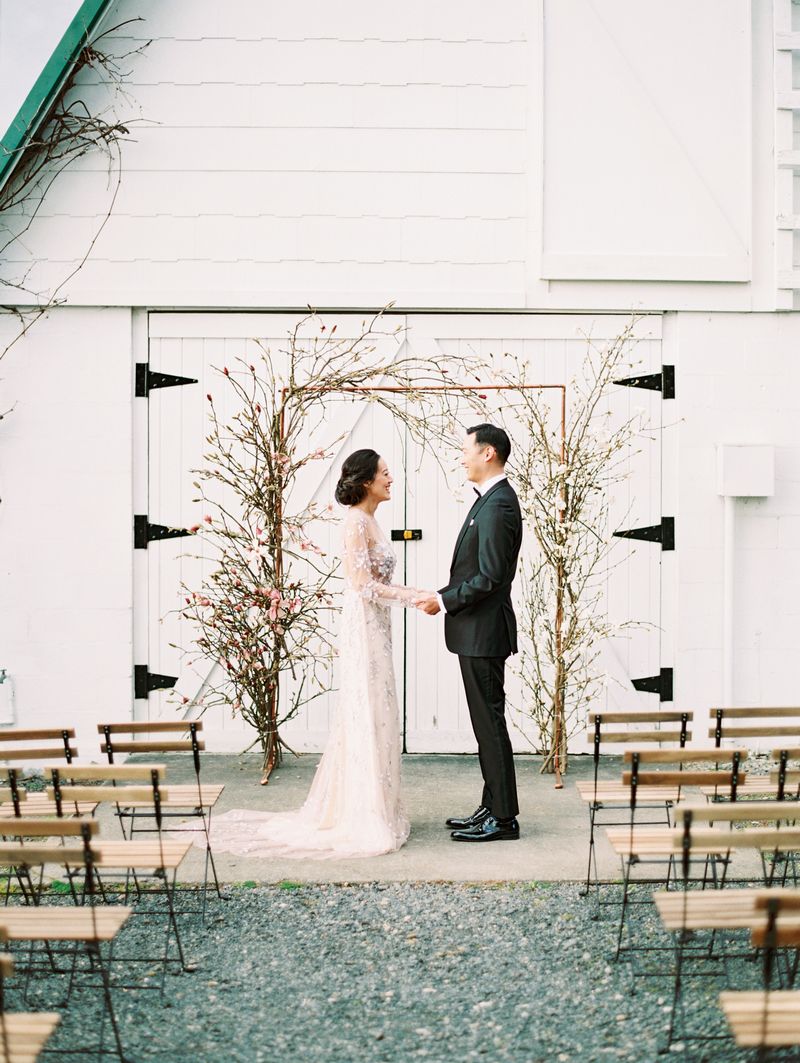 Bride and groom facing each other in front of magnolia floral ceremony arch