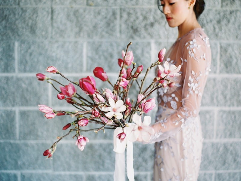 Bride holding large pink and white magnolia wedding bouquet