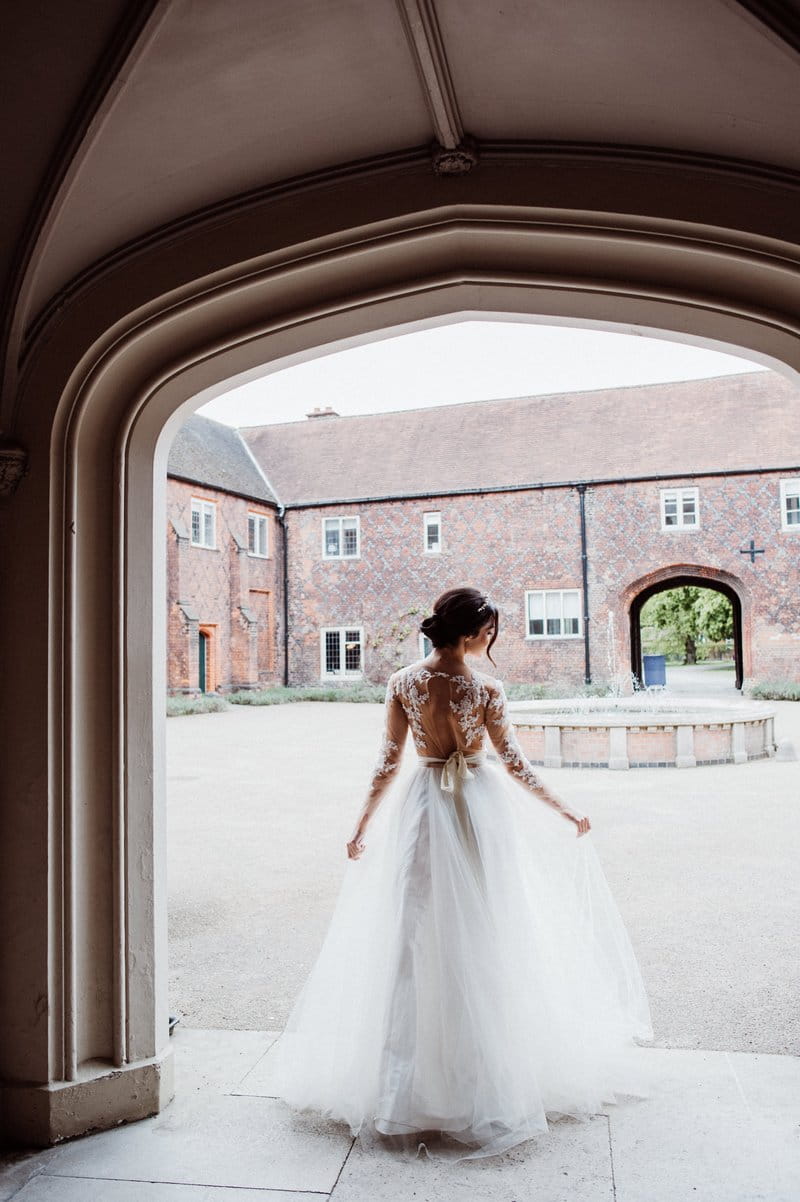 Bride standing at entrance to courtyard at Fulham Palace