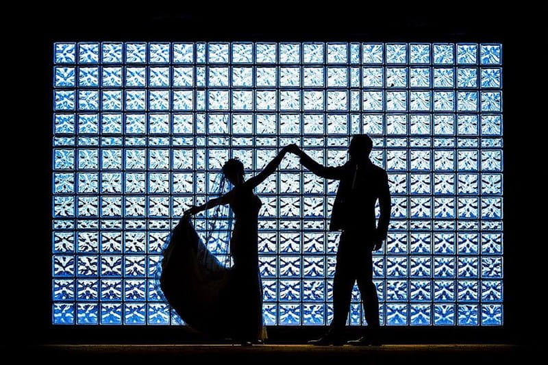 Silhouette of bride and groom against square glass wall - Picture by AV Fotoreportages