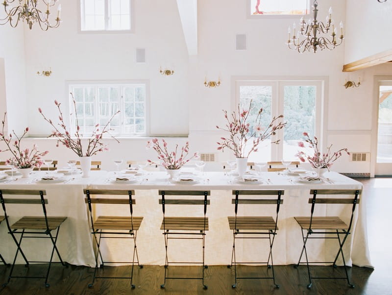 Wood and metal chairs at wedding table styled with pink and white magnolia flowers