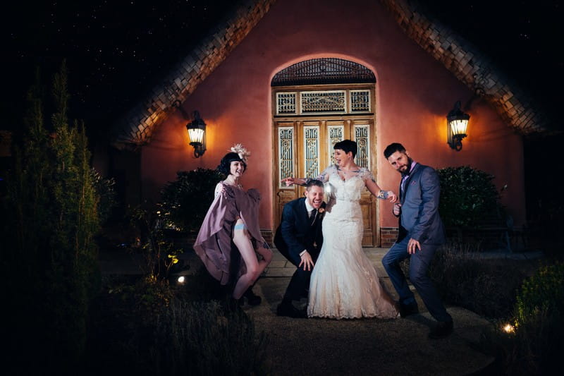 Bride and groom with friends outside Le Petit Chateau at night