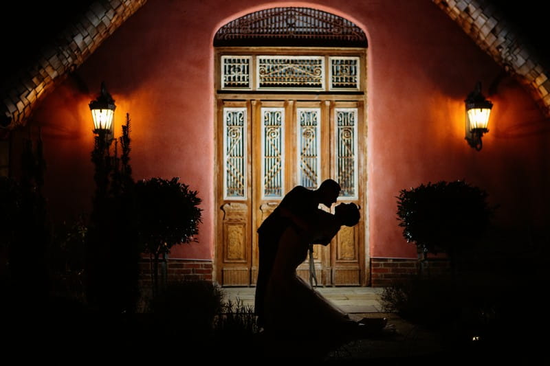 Silhouette of bride and groom outside Le Petit Chateau at night