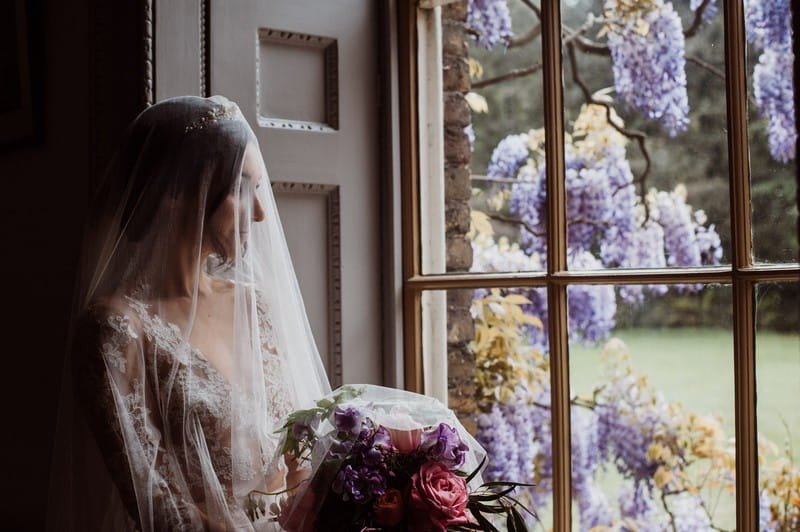 Bride with long veil looking out of the window at Fulham Palace