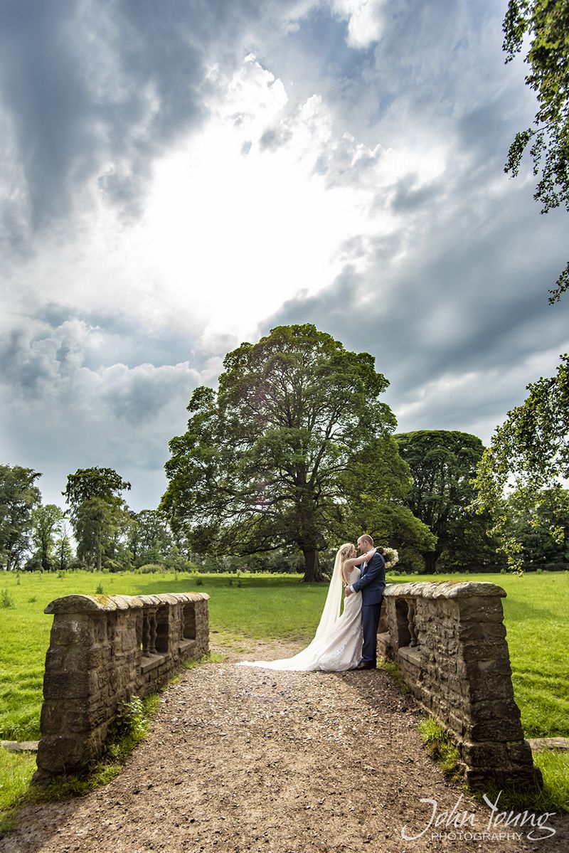 Bride and groom on small bridge with tress in the background - Picture by John Young Photography