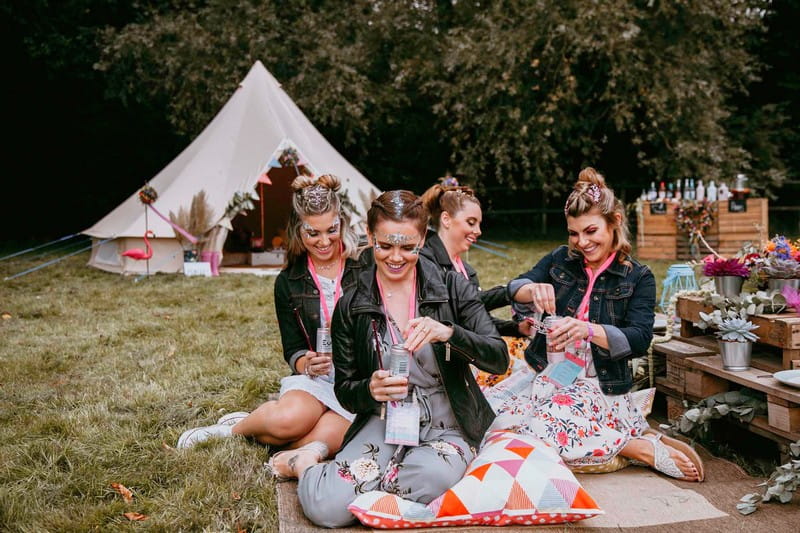 Girls sitting on rug at hen party opening drinks