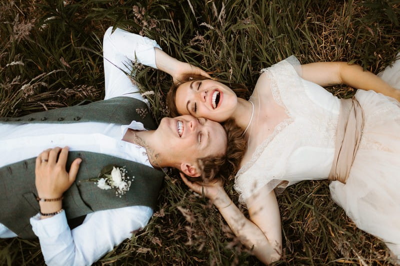 Bride and groom laying in grass with their heads touching - Picture by The Hendrys Photography