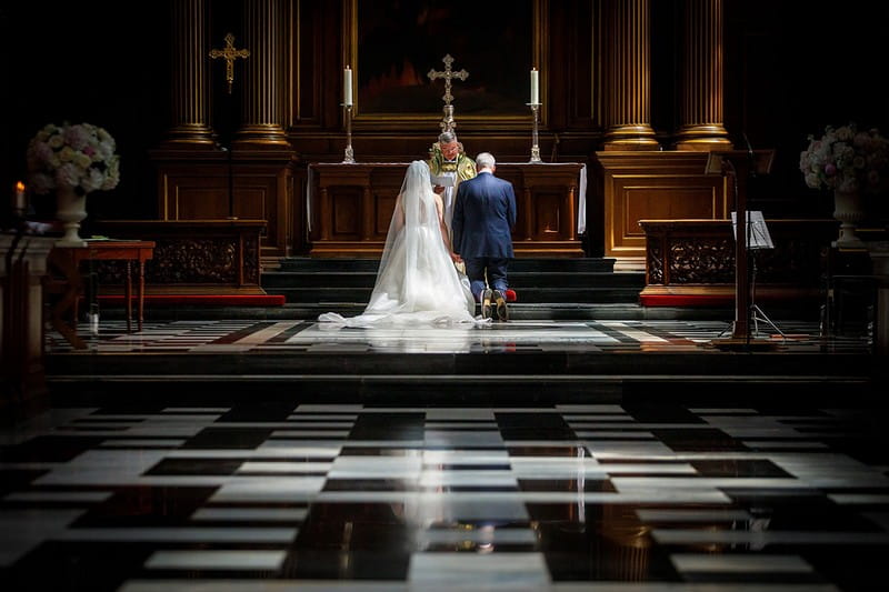 Bride and groom nealing at altar in front of priest - Picture by Duncan Kerridge Photography