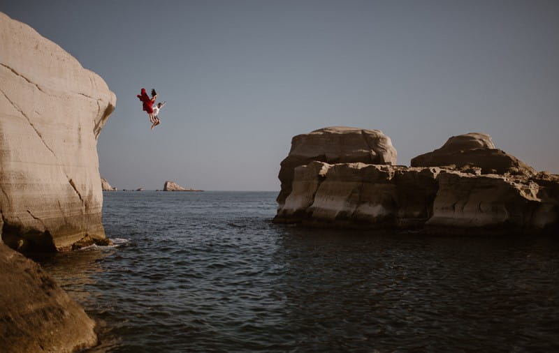 Couple jumping off cliff into the sea - Picture by Adventure Instead