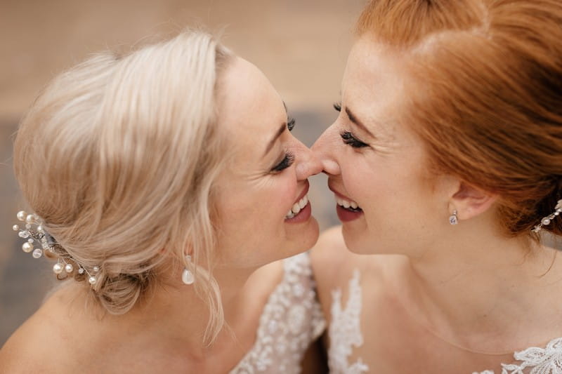 Two smiling brides touching noses - Picture by Jules Barron