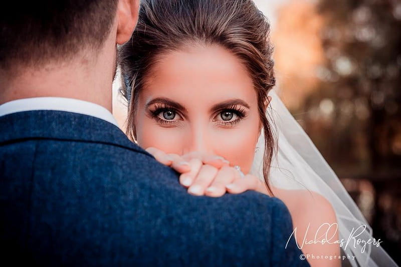 Bride looking over groom's shoulder staring into camera - Picture by Nicholas Rogers Photography