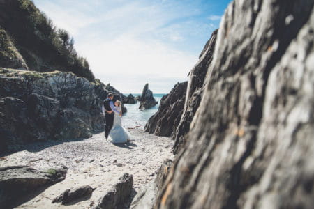 Bride and groom on beach amongst rocks - Picture by Andrew George Photography