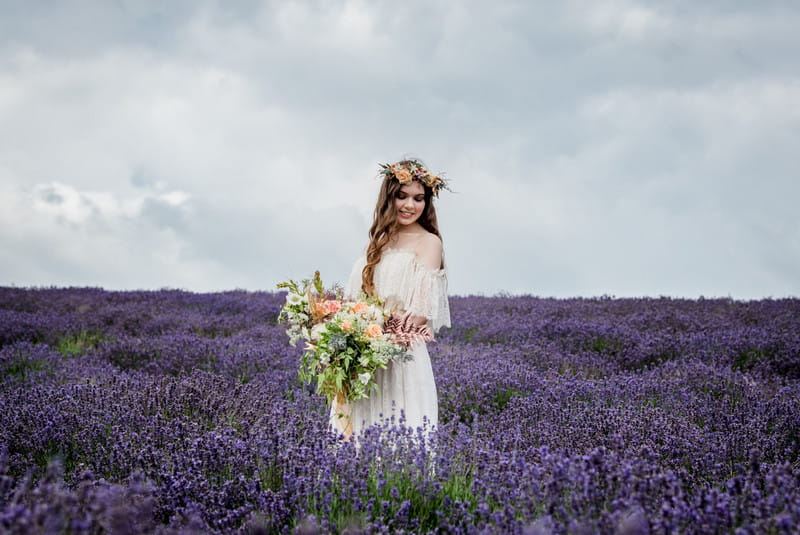 Bride holding bouquet in field of lavender