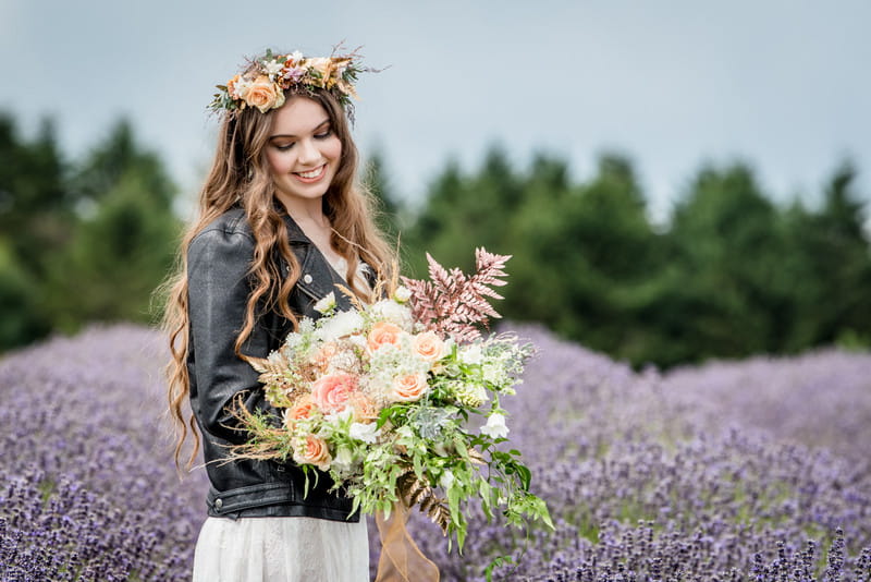 Bride wearing leather jacket standing in Cotswold Lavender Field