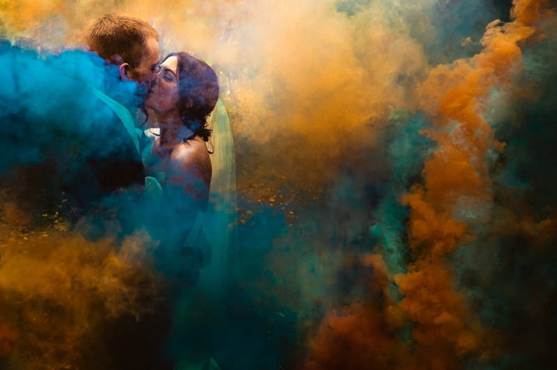 Bride and groom kissing surrrounded by orange and blue smoke - Picture by MSW Photos