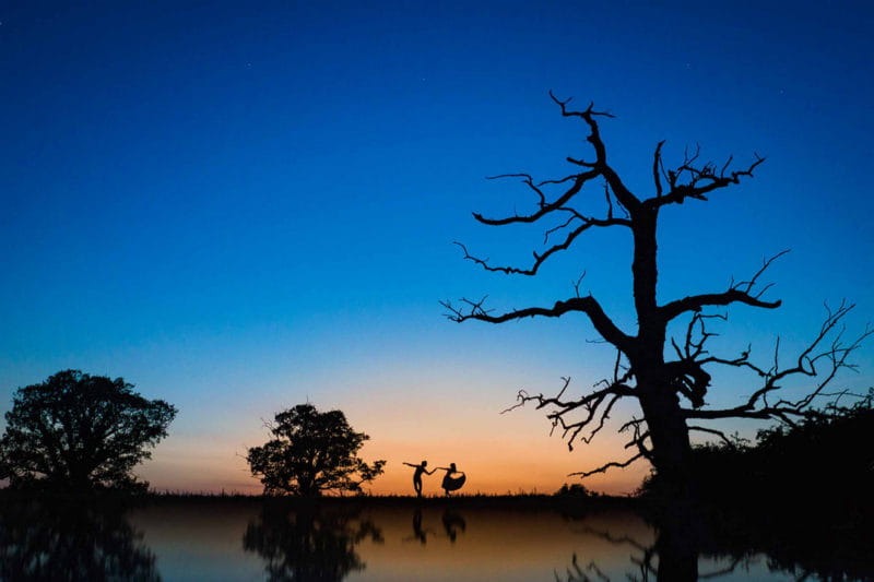 Silhouette of bride and groom dancing by trees at sunset - Picture by Alex Beckett Photography