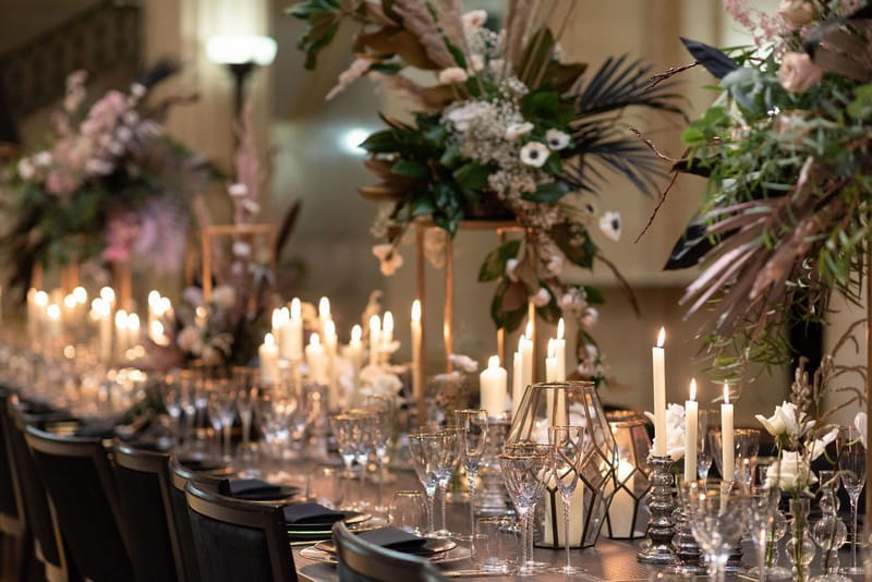Wedding table styled with candles and large floral displays