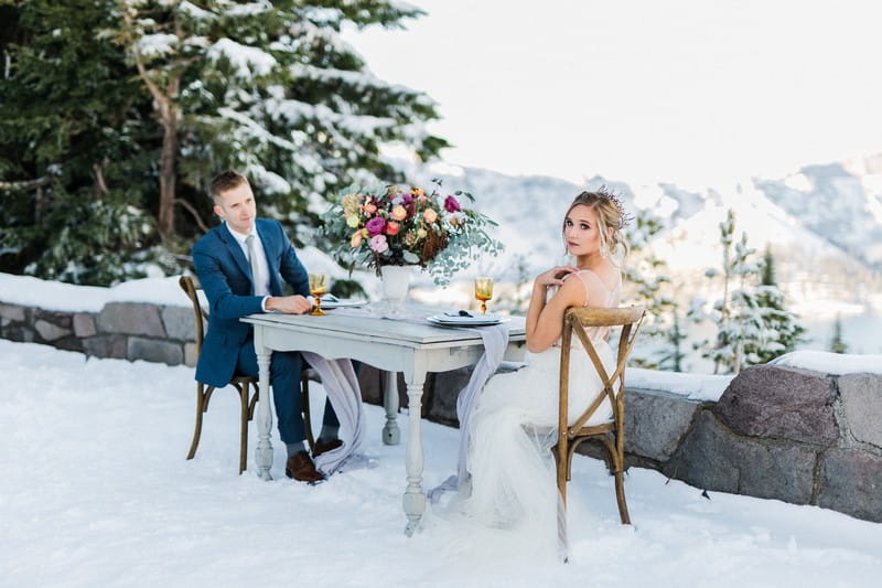 Bride and groom sitting at table outside in the snow