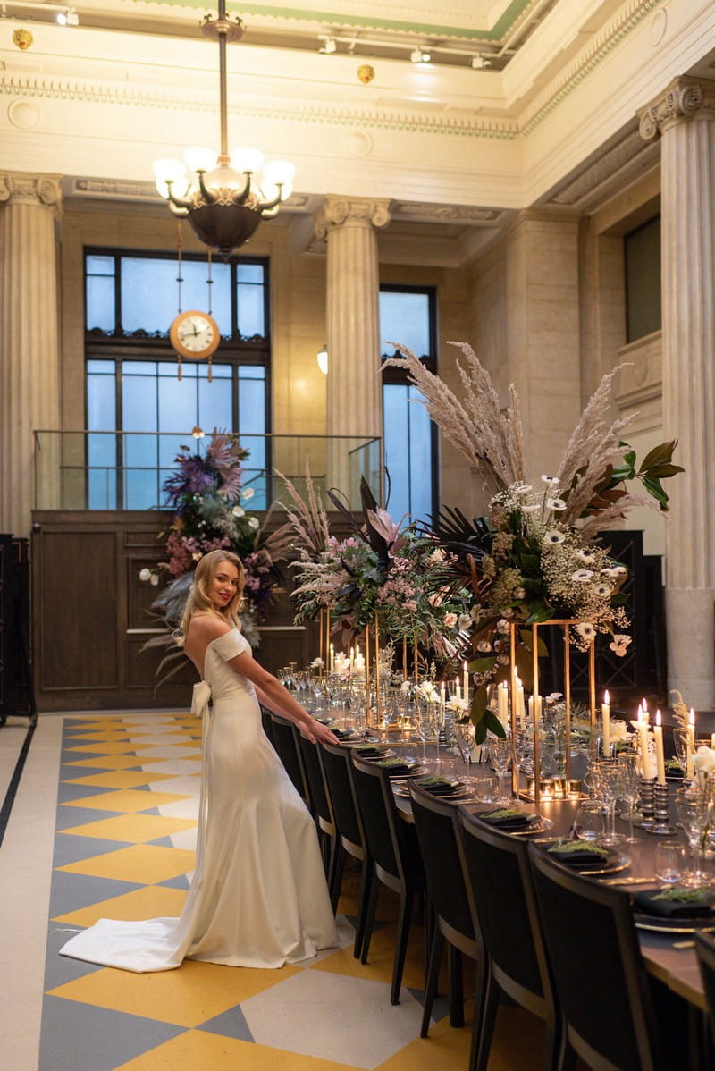 Bride standing next to long wedding table in Banking Hall, London