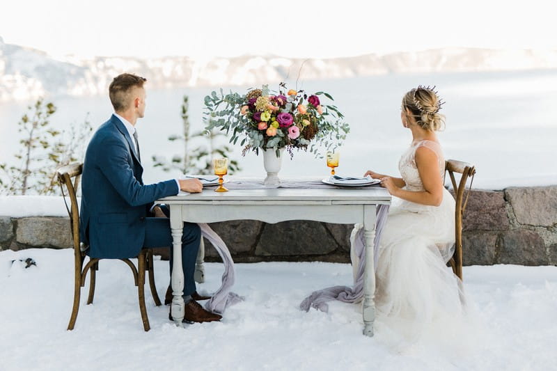 Bride and groom sitting at table looking at view of Crater Lake