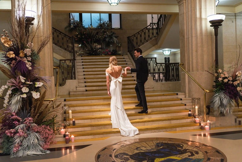 Bride and groom walking up stairs in Banking Hall in London