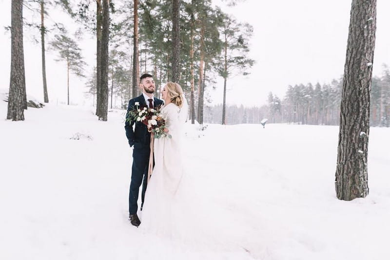 Bride and groom standing in the snow - Picture by Lucie Watson Photography