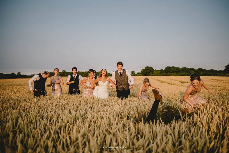 Man falling over as bridal party walk across corn field - Picture by Benjamin Mathers Photography