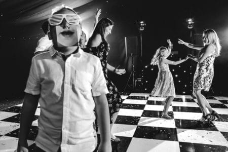 Boy on wedding dance floor wearing lasses and an image of a mouth - Picture by John Woodward Photography