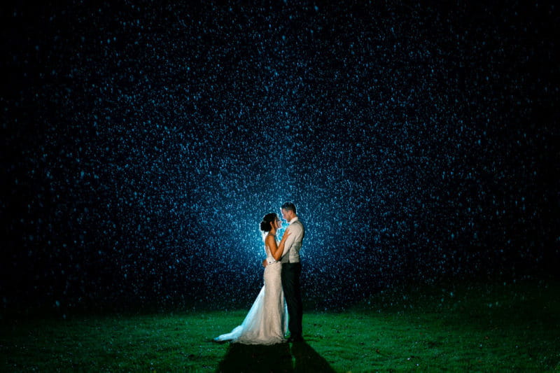 Bride and groom standing in the rain at night - Picture by Dean Jones Photography