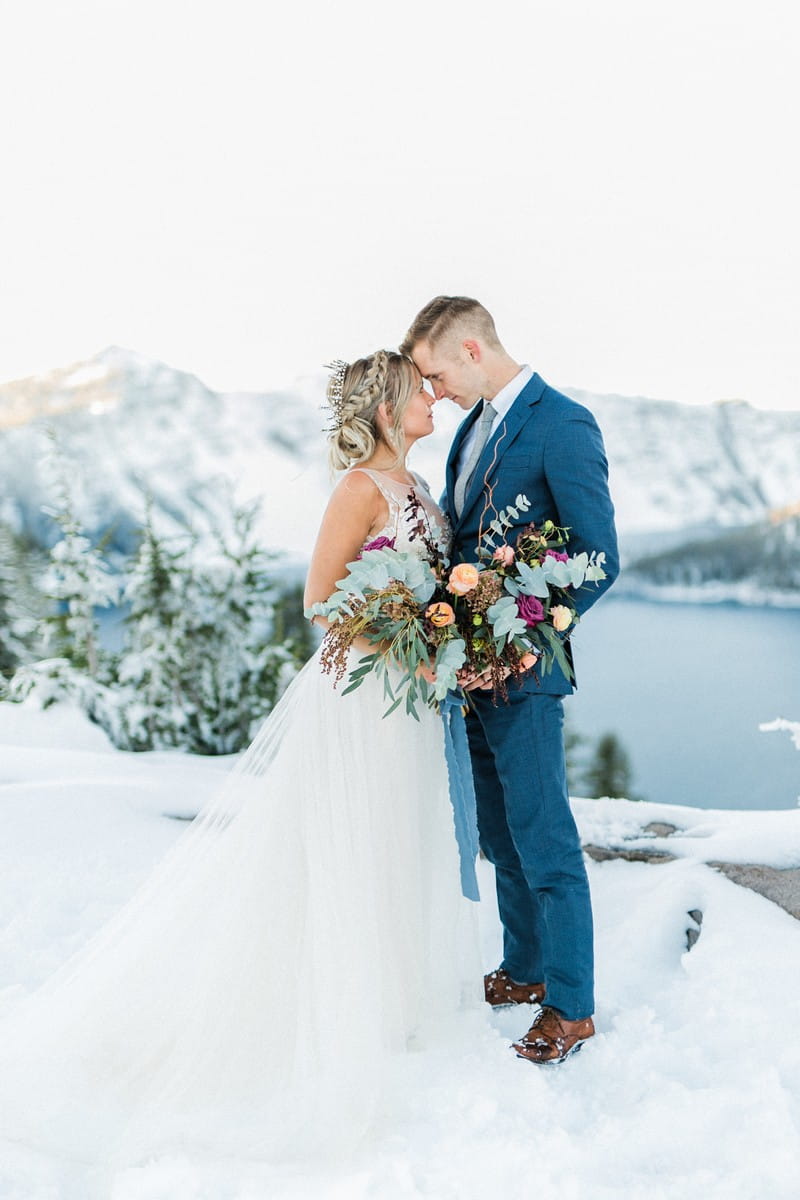 Bride and groom standing touching heads at Crater Lake