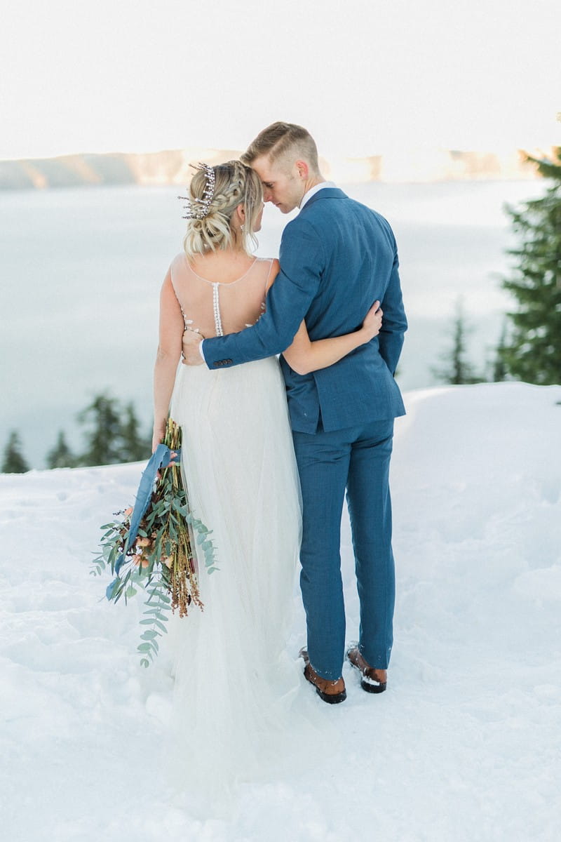 Bride and groom standing in snow at Crater lake