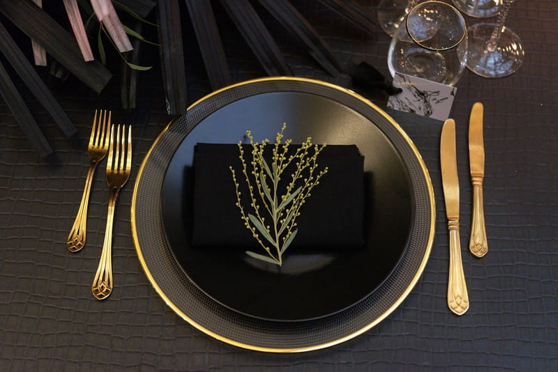 Black wedding place setting with gold cutlery
