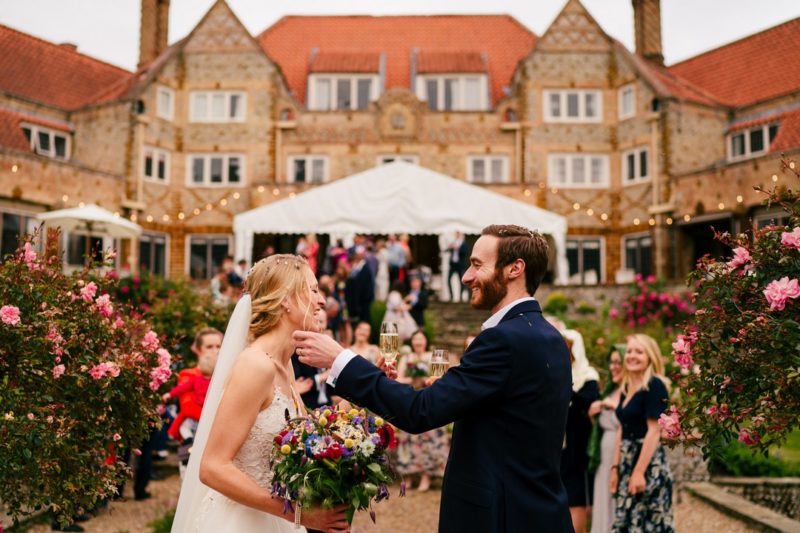 Grom picking confetti off of laughing bride - Picture by Gina Manning Photography