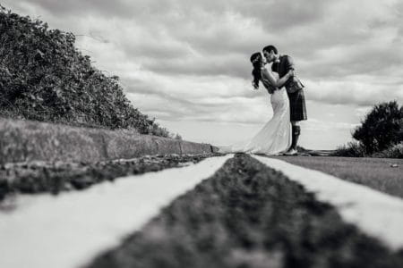 Bride and groom kissing standing in road next to double yellow lines - Picture by Joss Denham Photography