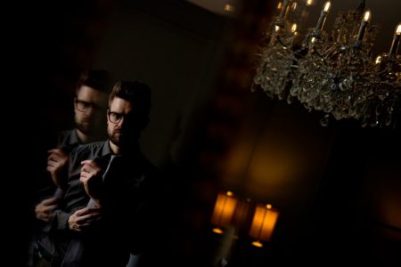 Groom getting ready for wedding in dark room - Picture by Matt Selby Photography