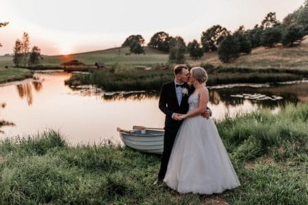 Bride and groom kissing by lake as sun sets - Picture by Ufniak Photography