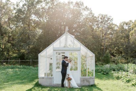 Bride and groom kissing in front of a greenhouse - Picture by Anette Bruzan Photography